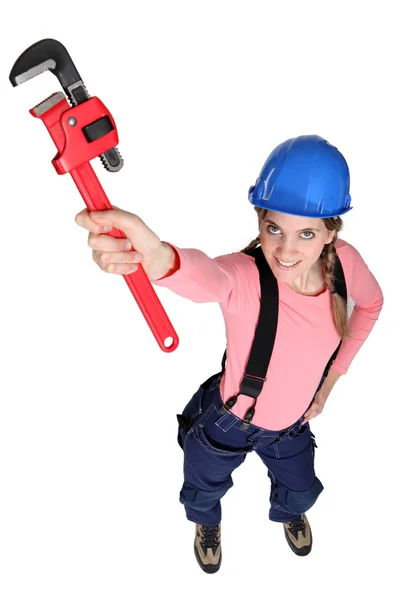 Handwerkerin hält einen Rohrschlüssel in die Höhe — Stockfoto