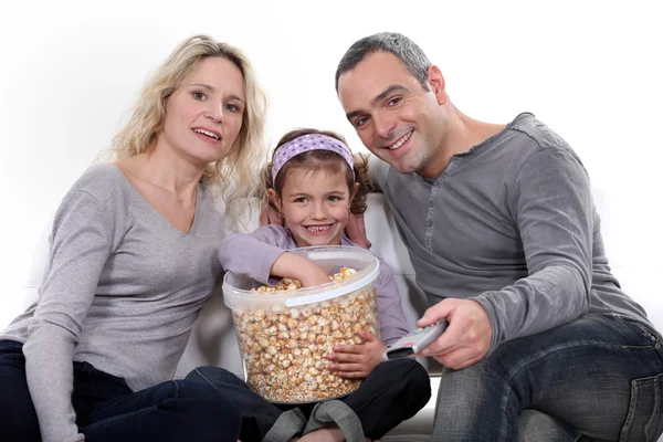 Família comer pipocas em um sofá — Fotografia de Stock