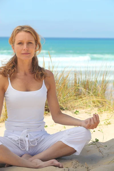 Vrouw doet yoga op het strand — Stockfoto