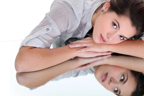 Junge Frau ruht ihren Kopf auf einer verspiegelten Oberfläche — Stockfoto