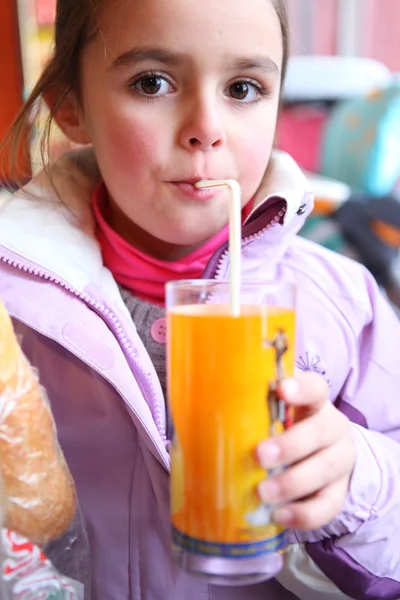 Little girl drinking juice using a straw — Stock Photo, Image