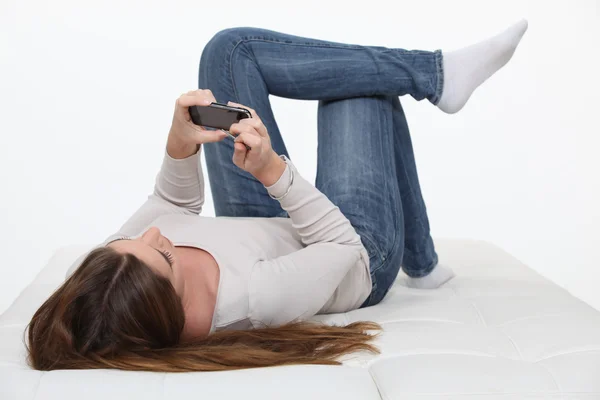 Mädchen liegt auf dem Rücken und schaut Film auf ihrem Handy — Stockfoto