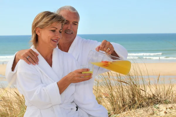 Paar in badjassen op het strand — Stockfoto