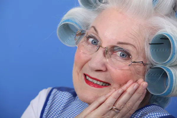 Elderly lady using hair rollers Stock Picture