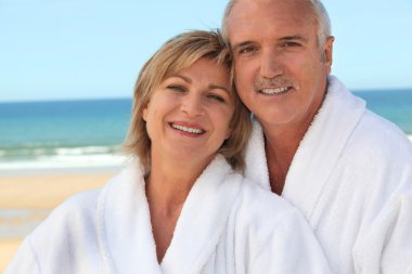 Couple at the beach in bathrobes clipart