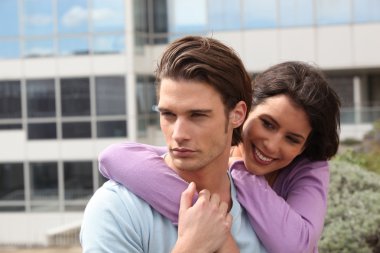 Couple embracing in front of building clipart