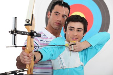 Teenage boy archery lesson clipart