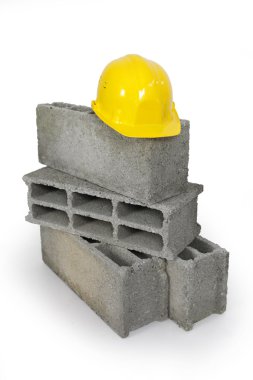 Yellow hard hat resting on pile of breeze blocks clipart