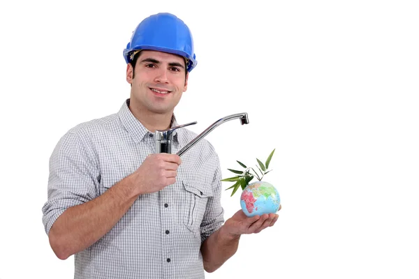 Klempner hält einen Wasserhahn über einen Mini-Globus — Stockfoto
