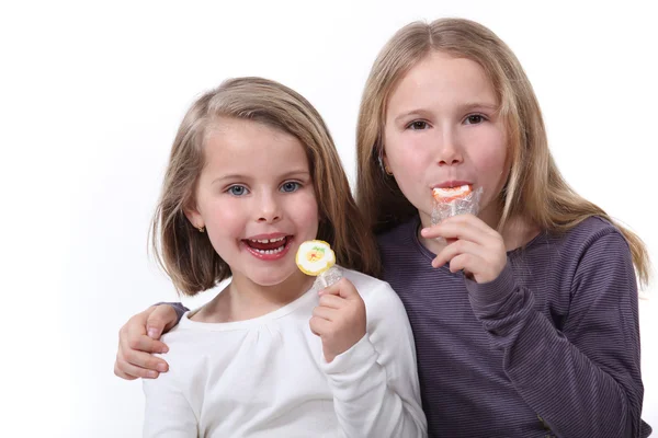 Two sisters eating lollipops. — Stock Photo, Image