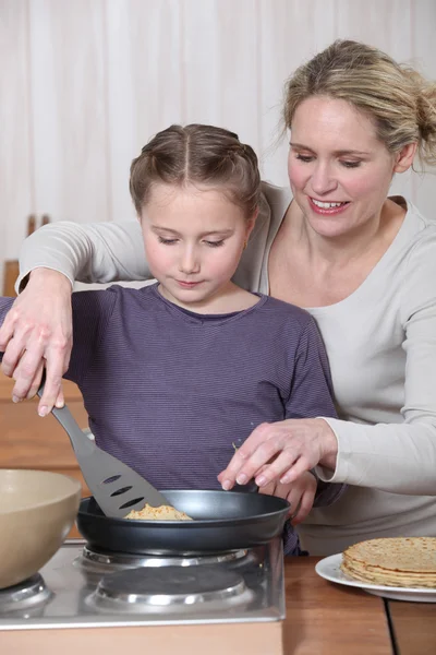 Nő és kislány főzés palacsinta — Stock Fotó