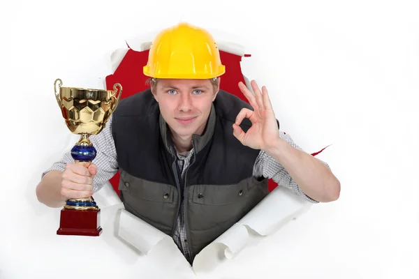 Будівельник з трофеєм робить знак Гаразд — стокове фото