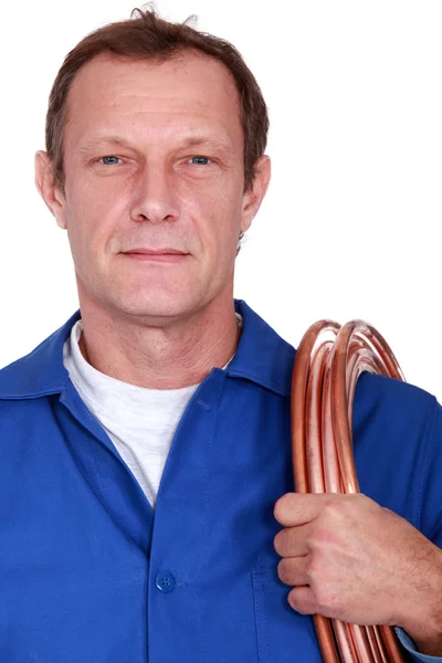 Plumber with coiled copper pipe over shoulder — Zdjęcie stockowe
