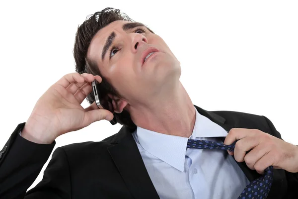 Businessman talking on the phone and taking off his tie — Stock Photo, Image