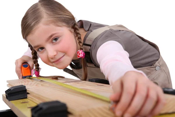 A child girl measuring a plank — Stock Photo, Image