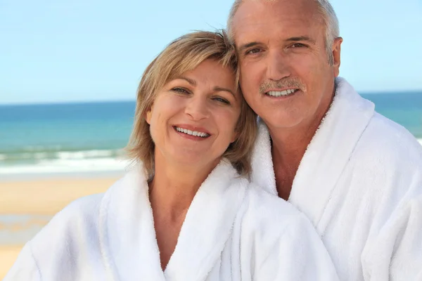Par på stranden i badrockar — ストック写真