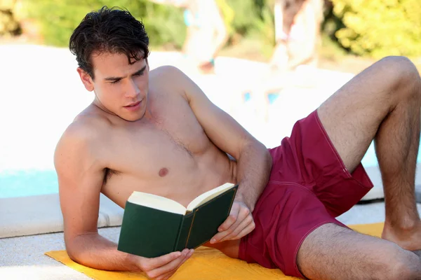 Chłopiec czytanie przy basenie — Zdjęcie stockowe