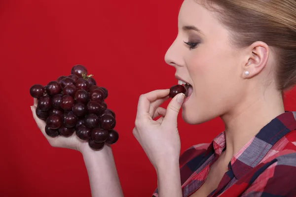 Женщина ест красный виноград — стоковое фото