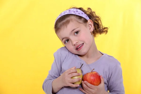 Маленькая девочка с яблоками в руке на желтом фоне — стоковое фото