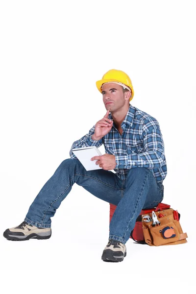 Builder satt på tool box tänkande — Stockfoto