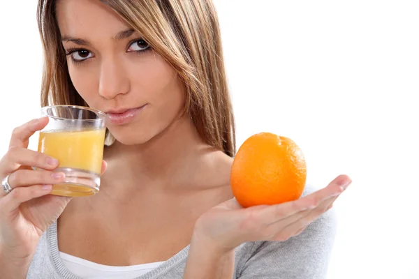 Mulher segurando suco de laranja e laranja — Fotografia de Stock