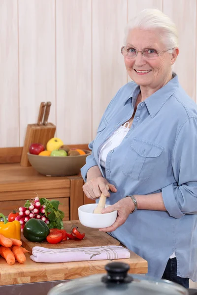 Mulher usando um pilão e argamassa na cozinha — Fotografia de Stock