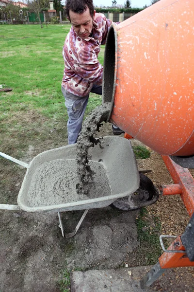 Mann schüttet Zement in Schubkarre — Stockfoto