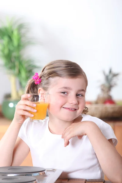 Menina loira bebendo suco de laranja na cozinha — Fotografia de Stock