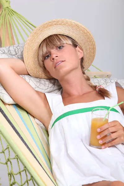 女人躺在吊床上喝水果鸡尾酒 — 图库照片