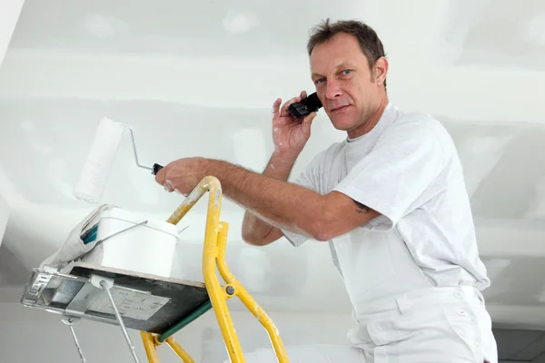 Painter on ladder making a call — Stock Photo, Image