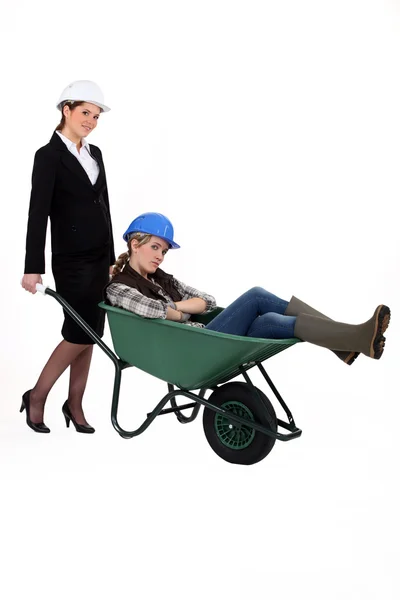 Female architect pushing colleague in wheelbarrow — Stock Photo, Image