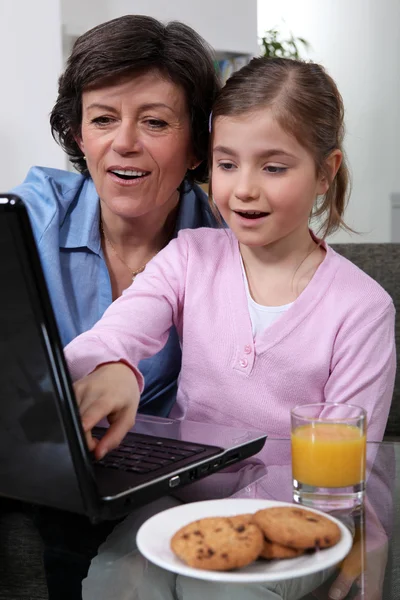 Kleines Kind schaut mit seiner Großmutter auf einen Laptop — Stockfoto
