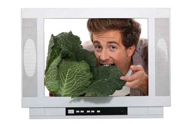 Mężczyzna jedzenie kapusta wewnątrz telewizora — Zdjęcie stockowe