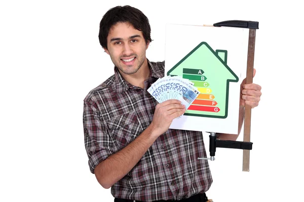 Muž drží značku spotřeby energie a spoustu peněz v hotovosti — Stock fotografie