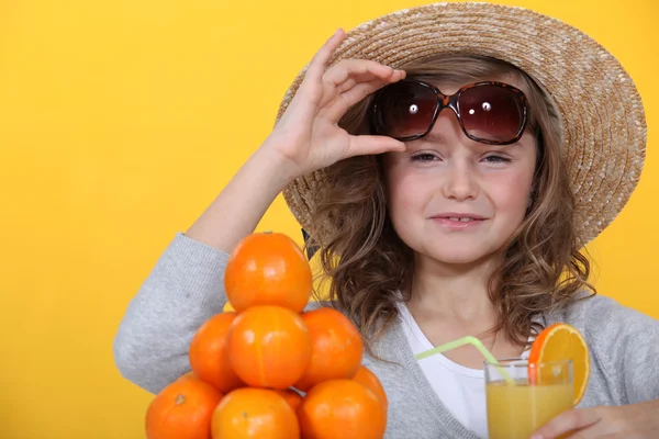 Little girl with pile of oranges wearing straw hat — Stock Photo, Image