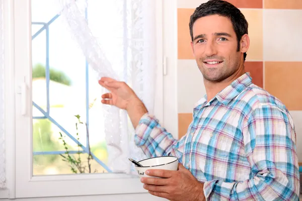 Muž s miskou, při pohledu z okna — Stock fotografie