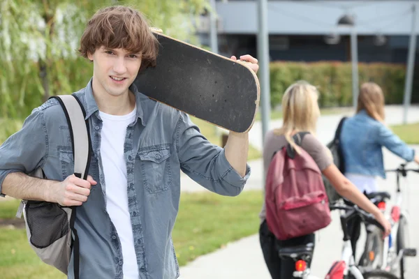 Студент на кампусе со скейтбордом — стоковое фото