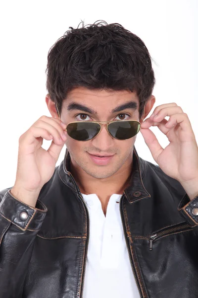 Fiatal férfi bőr kabát és divatos napszemüveget visel — Stock Fotó
