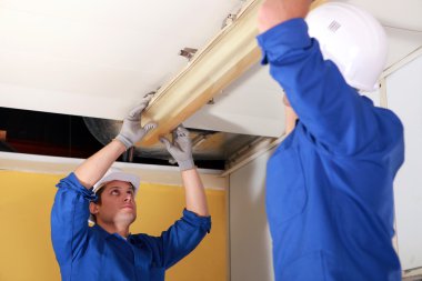 Electricians fixing neon on the ceiling clipart