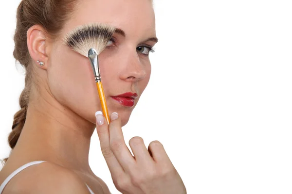 Femme tenant une brosse de maquillage devant son visage — Photo