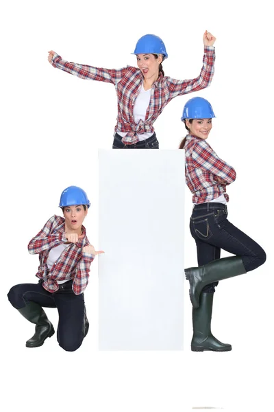 Triplets dancing around a blank sign — Stock Photo, Image