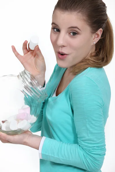 Cheeky woman eating marshmallow from jar — Stock Photo, Image