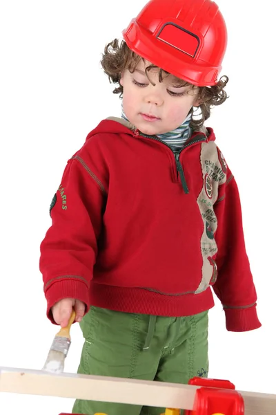 Carino bambino con pittura casco di plastica rosso — Foto Stock