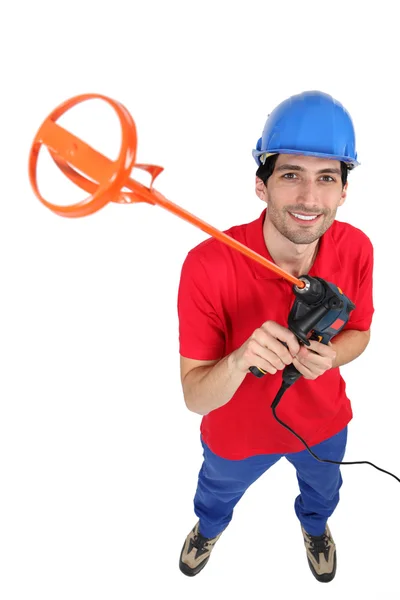 Tradesman holding up a tool for mixing mortar — Stock Photo, Image
