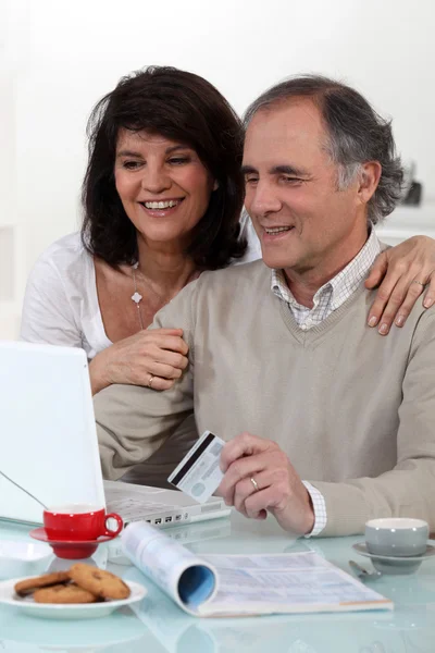 Vzorný manželský pár seděl u počítače s kreditní kartou — Stock fotografie