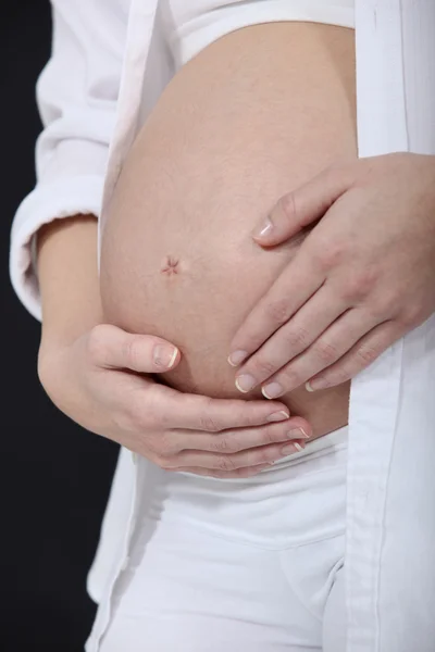 Женщина гладит свой беременный живот — стоковое фото