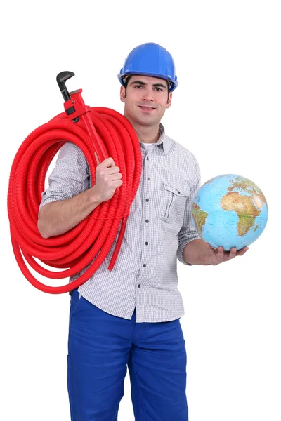 Ritratto di giovane idraulico che tiene il globo con un tubo sopra la spalla — Foto Stock
