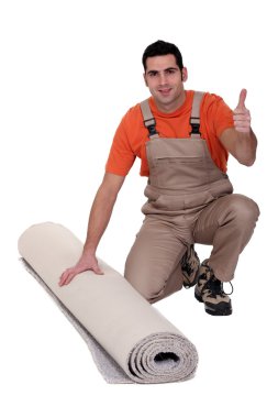 Man kneeling by rolled-up carpet clipart