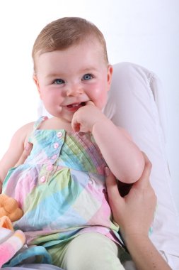 Blonde baby wearing a colorful dress and smiling clipart