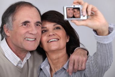 Middle aged couple taking a picture of themselves clipart